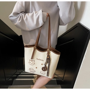 Detail showing the cartoon cat embroidery and MashaKeke logo on the beige tote bag