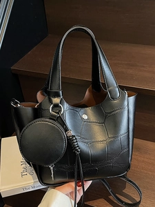 Sac seau noir élégant à motif crocodile avec porte-monnaie rond sur des marches en bois sombre