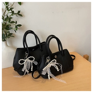Détail de sacs seaux en cuir litchi noir avec breloques en perles et dentelle élégantes