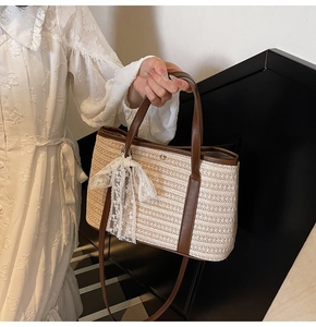 Détail d'un sac seau en paille tressée avec poignées en cuir et nœud en dentelle