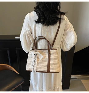 Détail d'un sac cabas en paille tissée avec finitions en cuir marron et nœud en dentelle