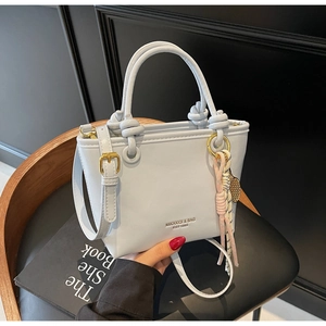 Detail view of ice blue bucket bag with round handles and braided rope charm pendant