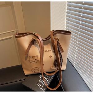 Detail shot of beige tote bag with cute cat embroidery and brown leather shoulder straps