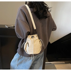 Detail der beigen Kordelzug-Beuteltasche mit seitlichen Netztaschen und Riemen