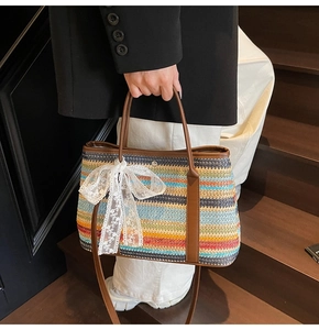 Détail du sac seau en paille arc-en-ciel avec poignées en cuir et nœud en dentelle blanche