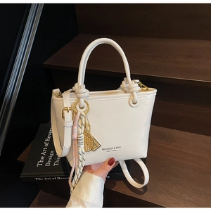 Detail of cream mini bucket bag with tennis racket charm and thin detachable strap