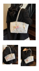 Close-up of elegant butterfly embroidery and pearl bow charm on cream lace shoulder bag