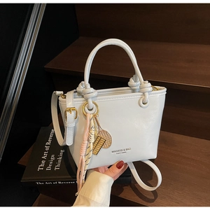 Detail view of white leather bucket bag with metal charms and branded logo text