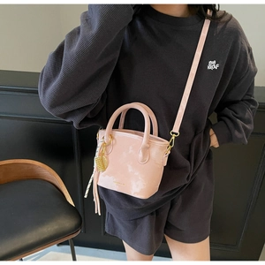 Detailed macro view of pink bucket bag with golden charms and elegant black-white tassels