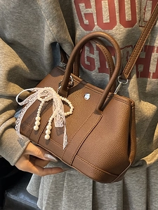 Sac seau marron en cuir avec nœud perlé et dentelle porté par un mannequin