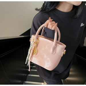 Detail of pink marble bucket bag with golden tennis racket charm and tassel on stairs