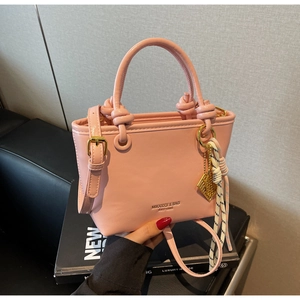 Pink matte leather bucket bag detail with decorative knot handle and striped silk scarf