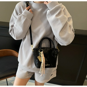 Detail of black marble textured bucket bag with golden abacus charm and long shoulder strap