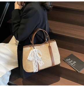 Détail du sac seau en paille tressée avec nœud en dentelle blanche et finitions cuir