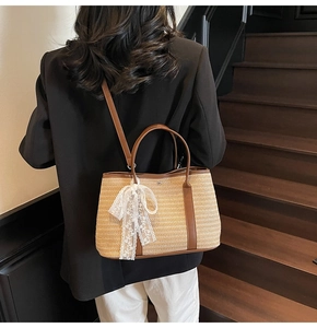 Détail du sac seau en paille tressée avec poignées en cuir marron et nœud en dentelle