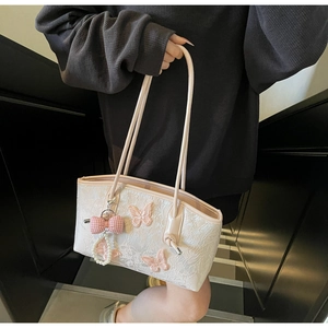 Detailed embroidery of pink butterflies on a cream faux leather underarm shoulder bag