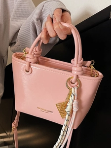 Pink glossy leather bucket bag with top handle and golden abacus charm for women
