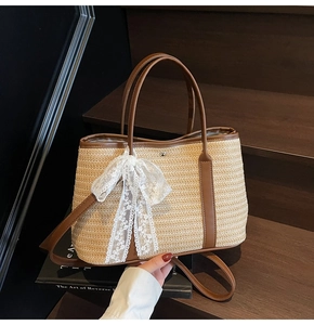 Détail d'un sac seau en paille avec poignées en cuir marron et nœud en dentelle décoratif
