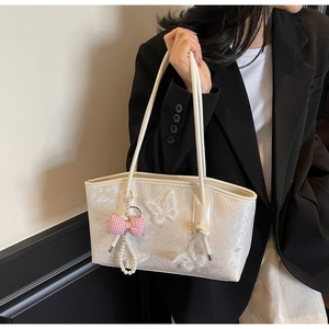 Detail of white lace embroidery and 3D butterfly appliqué on a stylish shoulder bag