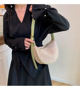 Detailed close-up of straw woven hobo bag with light green leather trim and strap