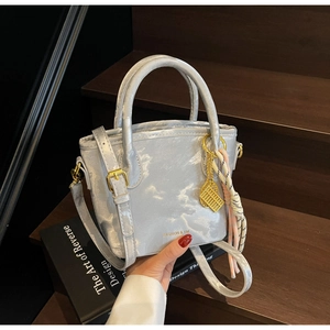 Detail of light blue satin mini tote with gold circular handles and abacus charm