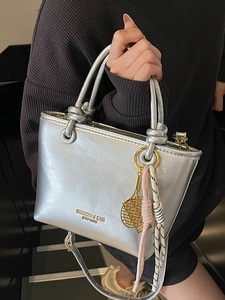 Classic silver metallic bucket bag with dual handles and woven charm for women