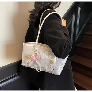 Detail of white tote bag featuring butterfly lace embroidery and pearl bow charm