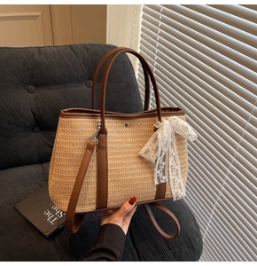 Détail du sac en paille avec nœud en dentelle et anses en cuir sur canapé