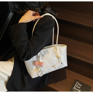 Detail of white tote bag featuring delicate butterfly embroidery and elegant pearl charm