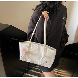 Detail of white lace tote bag with butterfly appliques and decorative pearl charms