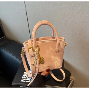 Detailed macro of a pink marble-textured bucket bag with gold hardware and logo detail