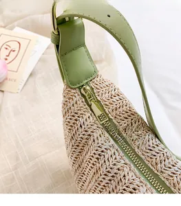 Detail of premium golden metal zipper and avocado green leather trim on straw woven bag