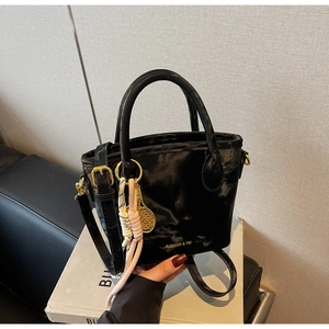 Detail of a black bucket bag with gold hardware and creative tennis racket charm
