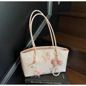 Close-up of beige shoulder bag featuring floral lace, pink butterfly embroidery and pearls
