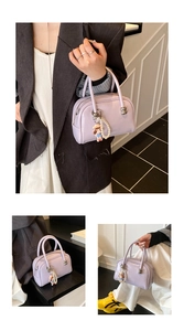 Detail view of light purple patent leather boston bag with pearl strap and cute doll pendant