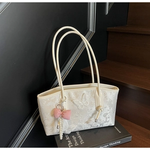 Detailed close-up of white lace butterfly embroidery and pearl charm on shoulder bag