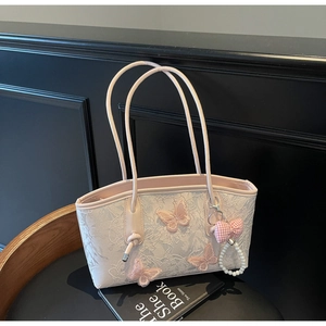 Close-up of the elegant 3D butterfly embroidery and pearl charm detail on the cream lace bag