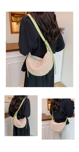 Detail of hand-woven straw crescent bag with green faux leather trim and metallic buckles