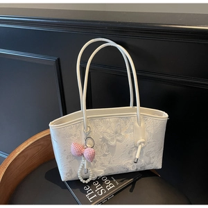 Detailed close-up of white lace tote bag featuring 3D butterfly embroidery and pearl charms