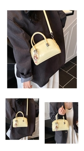 Three-way view of a cream Boston bag with a pearl doll pendant and silver ball lock