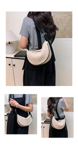 Close-up of beige woven straw dumpling bag with black leather straps and golden buckle detail