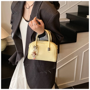 Chic cream pillow handbag with pearl charm shown in a cozy indoor lifestyle setting