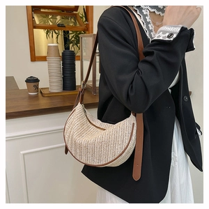 Detail of a woven crescent bag with brown leather trim and adjustable crossbody strap