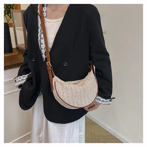 Close-up of contrast straw dumpling bag with leather strap worn by a female model