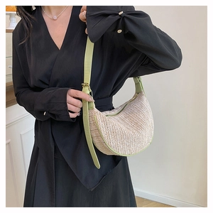 Detail of woven straw hobo bag featuring green leather trim and golden metal buckles