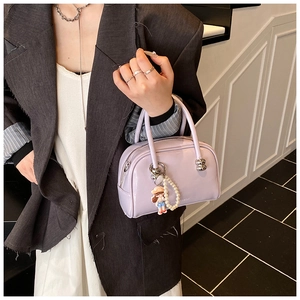 Detail showing light purple Boston bag with pearl strap and cute cartoon girl charm