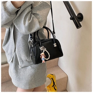 Detail of black patent leather Boston bag with pearl strap and cute cartoon charm