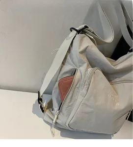 Detail view of the side zipper pocket on a large cream tote bag holding a pink wallet