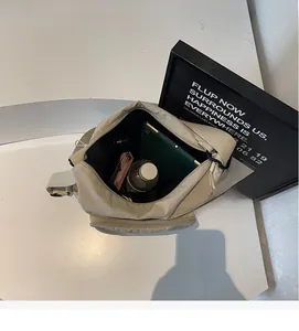 Detail view of the large capacity interior and zipper pocket of the beige nylon tote bag