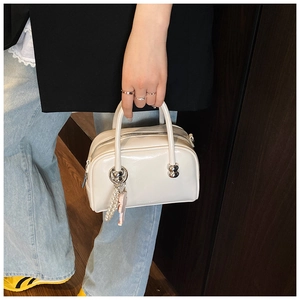 Detail view of cream white mini square bag with glossy finish and pearl pendant
